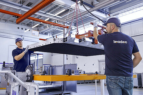 Two Leadec employees handling a battery housing.
